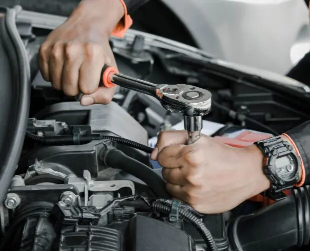 image-2 Mechanic using wrench on car engine.