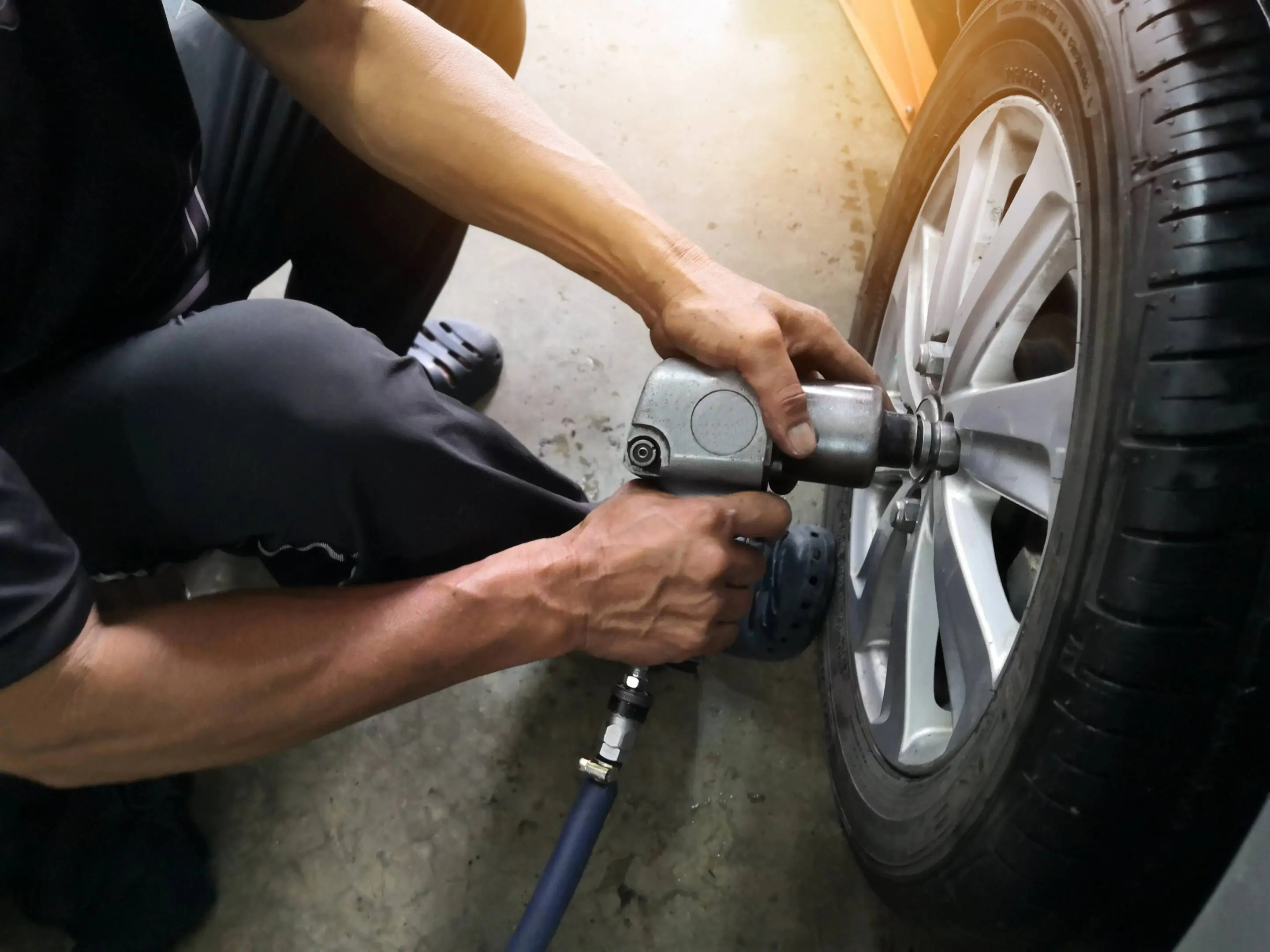 jpeg-optimizer_GettyImages-1176744449 Mechanic using impact wrench on tire.